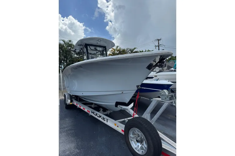 Slide: The Image of 2023 Sea Hunt Gamefish 27 Forward Seating boat on trailer, under cloudy sky. - 2