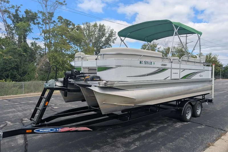 The Image of 2021 Qwest LS 822 DS Bar pontoon boat on trailer, green canopy, parked outdoors. - 1