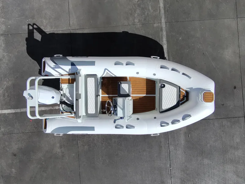 Slide: The Image of 2025 Tide Craft Catalina 13 boat, aerial view, white and wood accents, docked on concrete surface. - 3