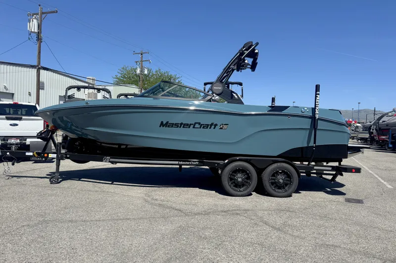 The Image of 2026 MasterCraft XT23 boat on trailer in parking lot, side view. - 0