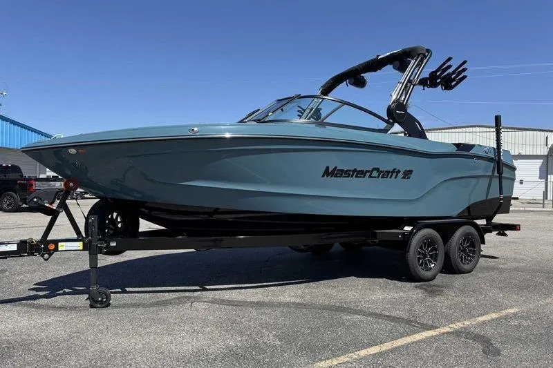 Slide: The Image of 2026 MasterCraft XT23 boat on trailer, parked outdoors under clear blue sky. - 5