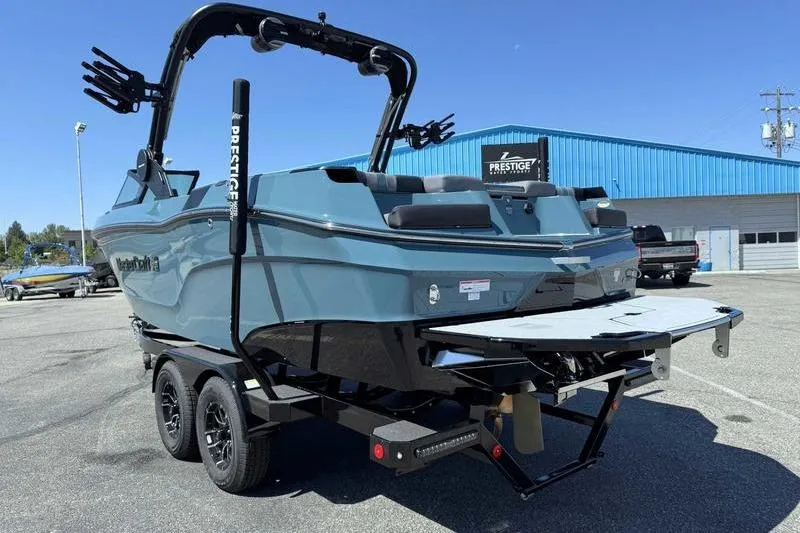 Slide: The Image of 2026 MasterCraft XT23 boat on trailer, parked outdoors near blue building. - 7