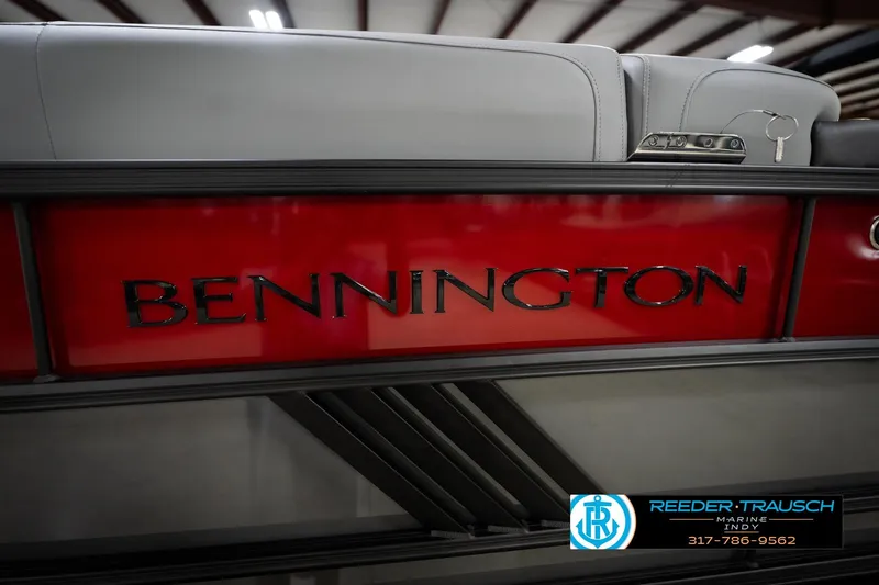 Slide: The Image of 2026 Bennington 22 MFB boat with red paneling and logo, showcased indoors. - 51