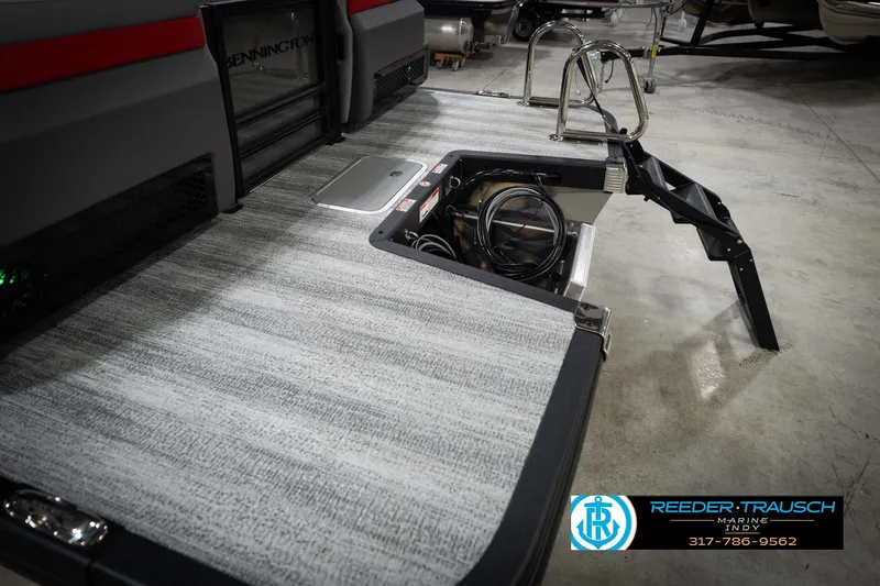 Slide: The Image of 2026 Bennington 22 MFB boat with open storage compartment and ladder, displayed indoors. - 54