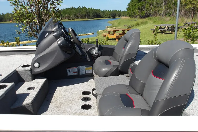Slide: The Image of 2022 Tracker Pro Team 190 TX Tournament Edition boat interior with gray seats by a lake. - 2