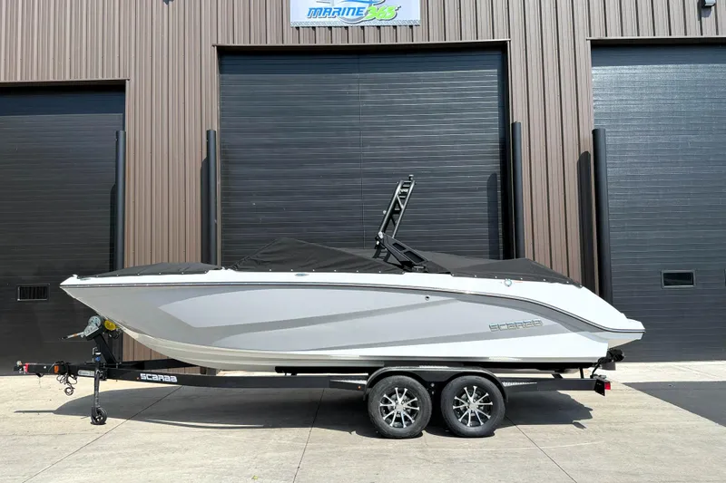Slide: The Image of 2026 Scarab 235 SE boat on trailer, parked outside a building. - 1