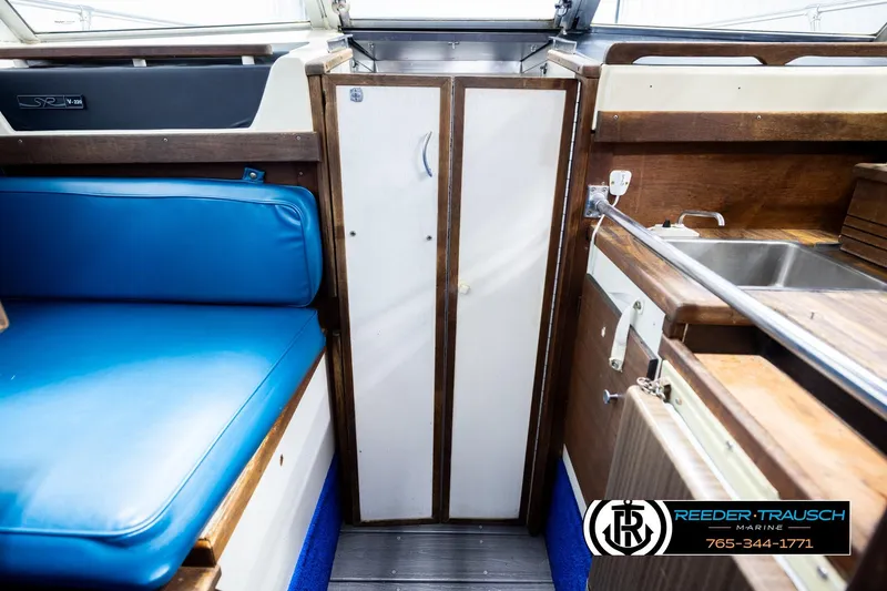 Slide: The Image of 1977 Searay 220 OV boat interior with blue seating, wooden cabinetry, and stainless steel sink. - 22