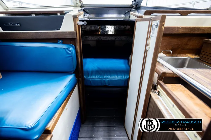 Slide: The Image of 1977 Searay 220 OV boat interior with blue seating and compact kitchenette. - 23