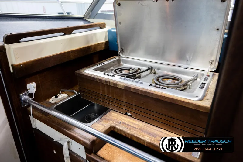 Slide: The Image of 1977 Searay 220 OV boat interior with stove and sink in wooden cabinetry. - 25