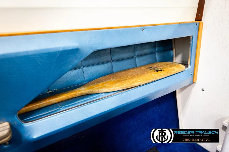 Slide: The Image of 1977 Searay 220 OV boat interior with blue storage compartment and wooden paddle. - 50