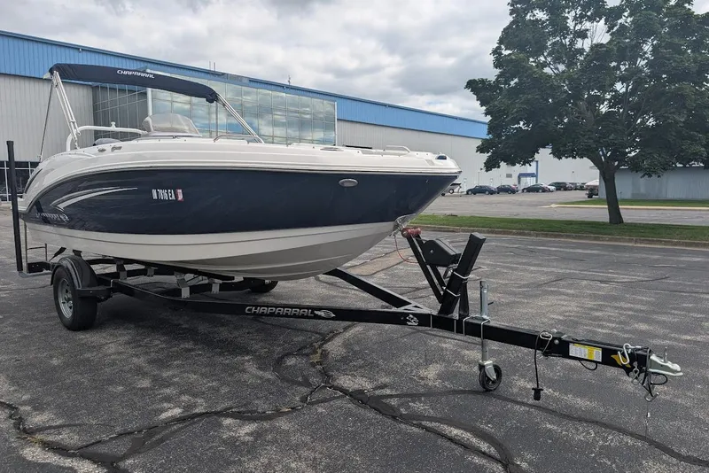 Slide: The Image of 2018 Chaparral 191 Suncoast boat on trailer, parked outdoors near industrial building. - 2