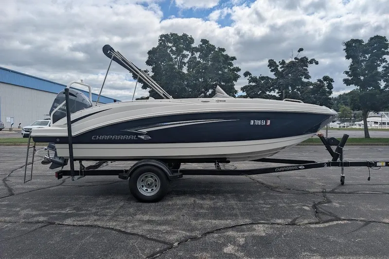 Slide: The Image of 2018 Chaparral 191 Suncoast boat on trailer, parked outdoors under cloudy sky. - 3
