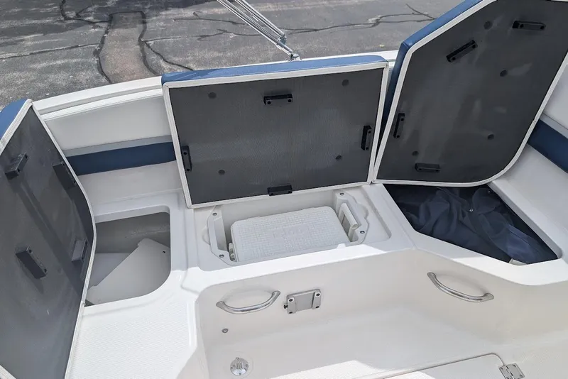 Slide: The Image of 2018 Chaparral 191 Suncoast boat storage compartments with open hatches and visible cooler. - 8