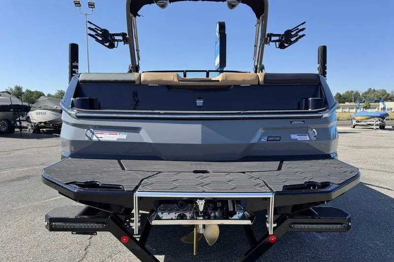 Slide: The Image of 2026 MasterCraft NXT22 boat rear view, showcasing swim platform and wakeboard racks. - 9
