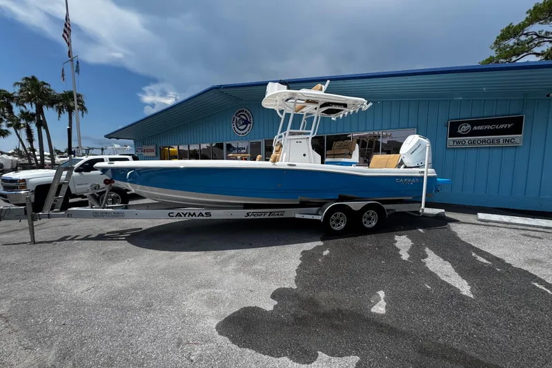 The Image of 2026 Caymas 28 HB boat on trailer outside dealership, blue hull, sunny day. - 0