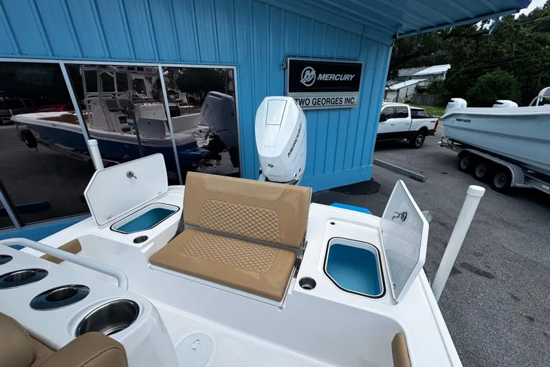 Slide: The Image of 2026 Caymas 28 HB boat with Mercury engine at dealership, featuring tan seating and storage compartments. - 15