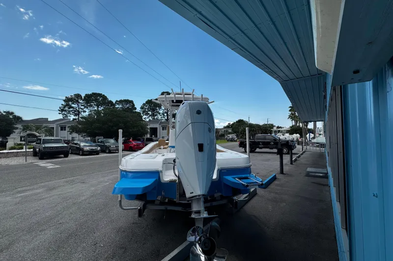 Slide: The Image of 2026 Caymas 28 HB boat on trailer outside a blue building under a cloudy sky. - 3