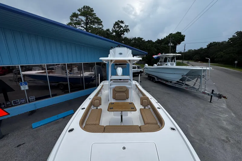 Slide: The Image of 2026 Caymas 28 HB boat with tan seating, parked near a blue building. - 6
