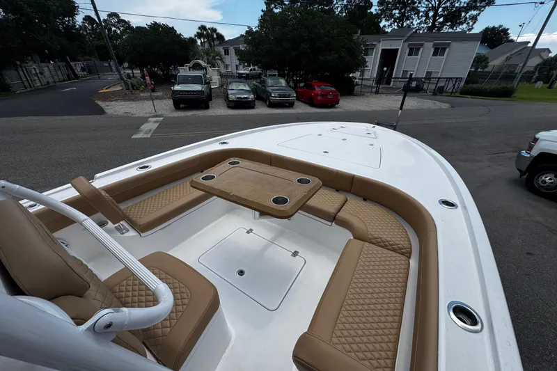 Slide: The Image of 2026 Caymas 28 HB boat with tan seating and table, parked in a residential area. - 8