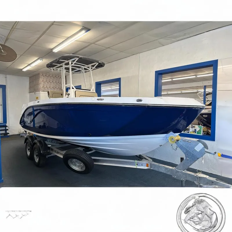 The Image of 2026 Yamaha Boats 222 FSH Sport in showroom, blue and white design on trailer. - 0