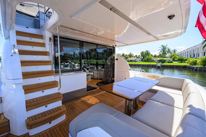 Slide: The Image of Luxurious 2020 Princess F70 yacht deck with seating, table, and staircase, overlooking serene waterfront. - 70