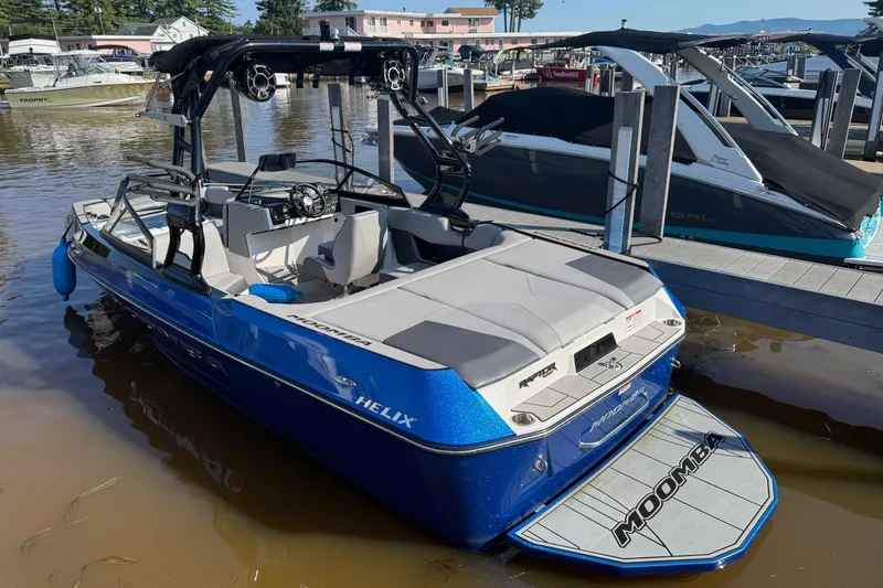 Slide: The Image of 2019 Moomba Helix boat docked, blue exterior, spacious interior, ready for water activities. - 1