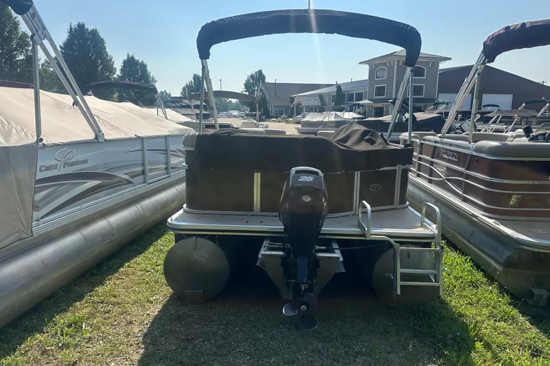 Slide: The Image of 2011 Harris Cruiser 200 pontoon boat with outboard motor, parked outdoors. - 11