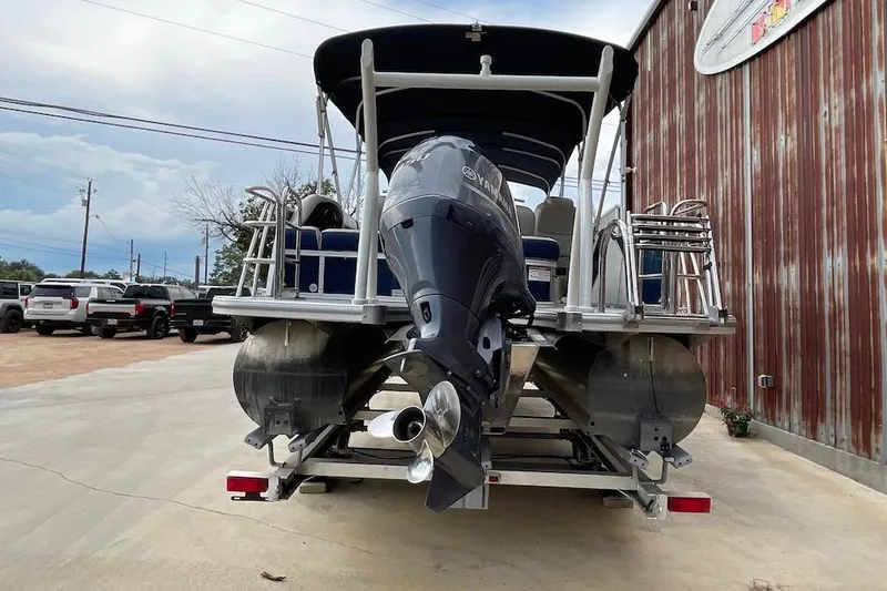 Slide: The Image of 2020 South Bay 523 pontoon boat with Yamaha outboard motor, parked near a metal building. - 3