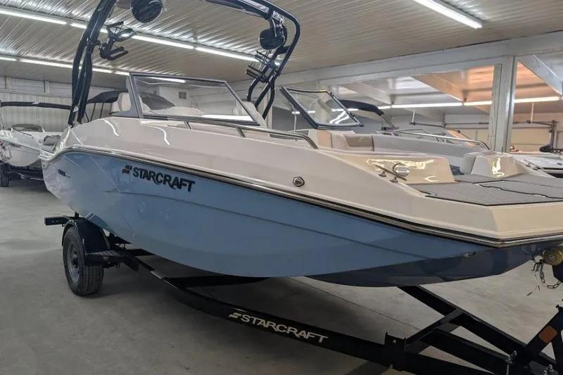 The Image of 2025 Starcraft SVX 210 IO boat in showroom, sleek design on trailer. - 1