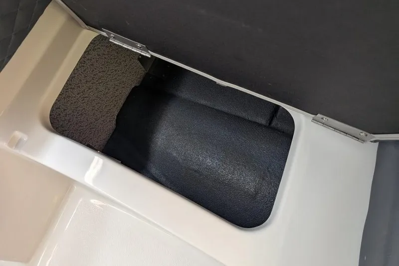 Slide: The Image of Storage compartment in 2025 Starcraft SVX 210 IO boat, featuring a hinged lid and carpeted interior. - 7