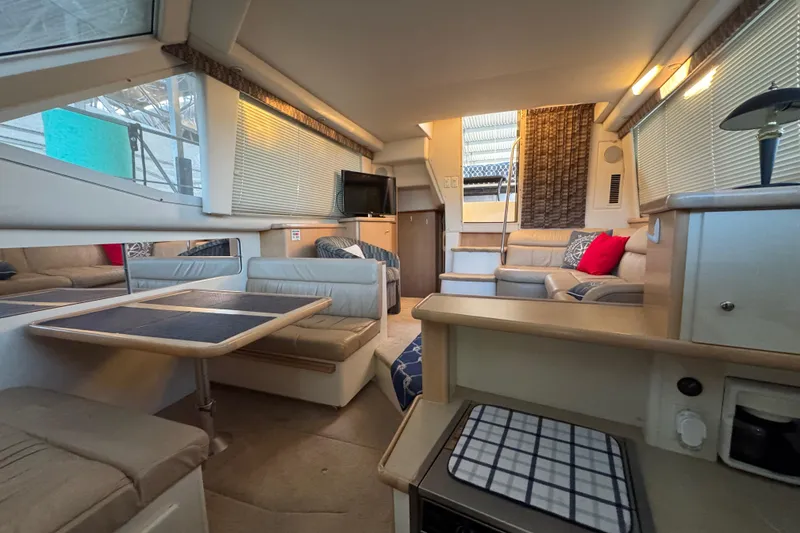 Slide: The Image of 1998 Carver 356 Aft Cabin interior with seating, table, and TV in a cozy setting. - 12