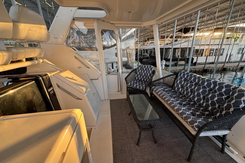 Slide: The Image of 1998 Carver 356 Aft Cabin interior with seating area and glass table in marina setting. - 4