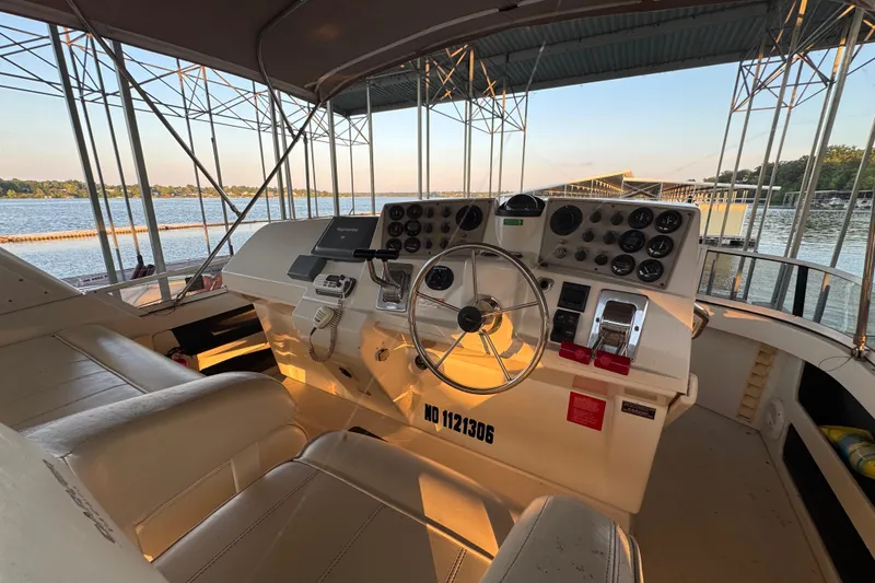 Slide: The Image of 1998 Carver 356 Aft Cabin boat helm with steering wheel and control panel, docked by the water. - 6