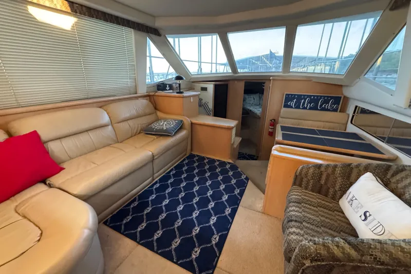 Slide: The Image of 1998 Carver 356 Aft Cabin interior with beige seating, nautical decor, and large windows. - 8