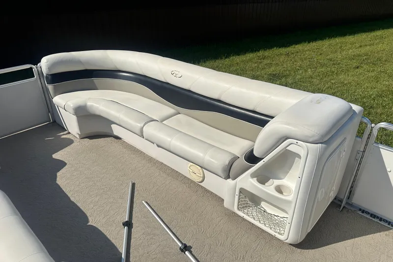 Slide: The Image of 2005 Harris Classic 260 boat interior with white and black seating, cup holders, and carpeted floor. - 6