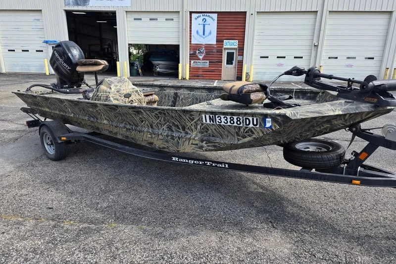 Slide: The Image of 2014 Ranger 1862 MPV boat with camouflage design on a trailer, parked outside a garage. - 1
