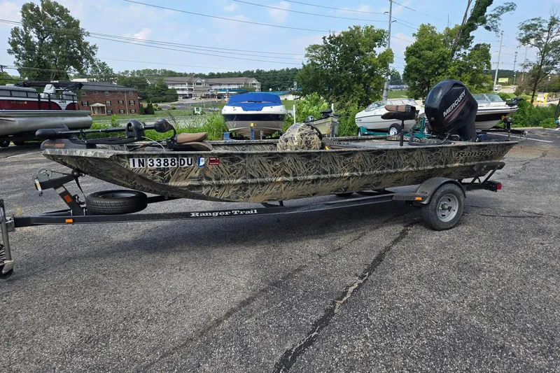 Slide: The Image of 2014 Ranger 1862 MPV camo boat on trailer, parked outdoors with other boats. - 4