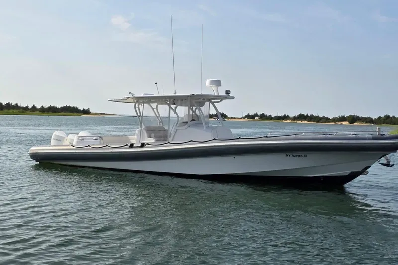 The Image of 2015 Yellowfin RIB boat on calm water, clear sky, shoreline in background. - 1