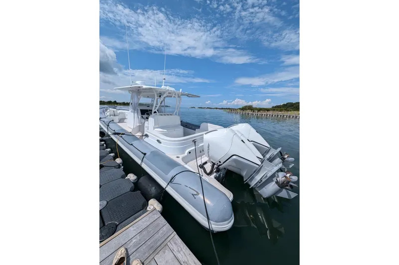 Slide: The Image of 2015 Yellowfin RIB boat docked on calm water under a blue sky. - 6