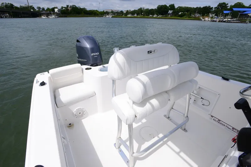 Slide: The Image of 2015 Sea Hunt Triton 210 boat interior with seating and outboard motor on calm water. - 12