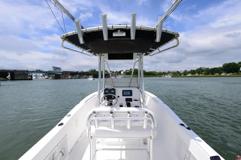 Slide: The Image of 2015 Sea Hunt Triton 210 boat on calm water, featuring a central console and T-top. - 13