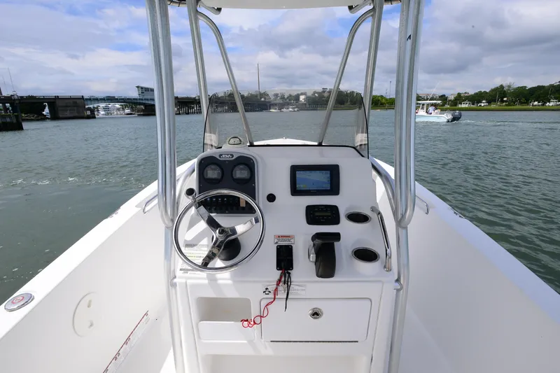Slide: The Image of 2015 Sea Hunt Triton 210 boat dashboard with steering wheel and controls on water. - 14