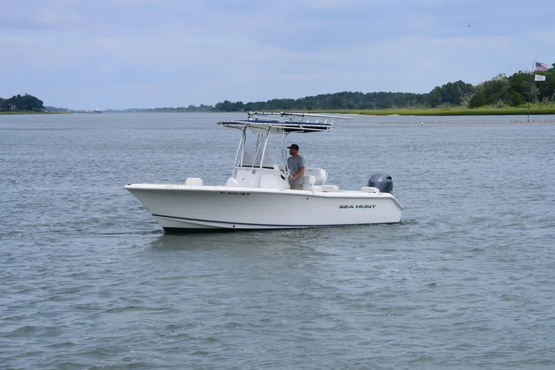 Slide: The Image of 2015 Sea Hunt Triton 210 boat cruising on a calm lake with a person onboard. - 8