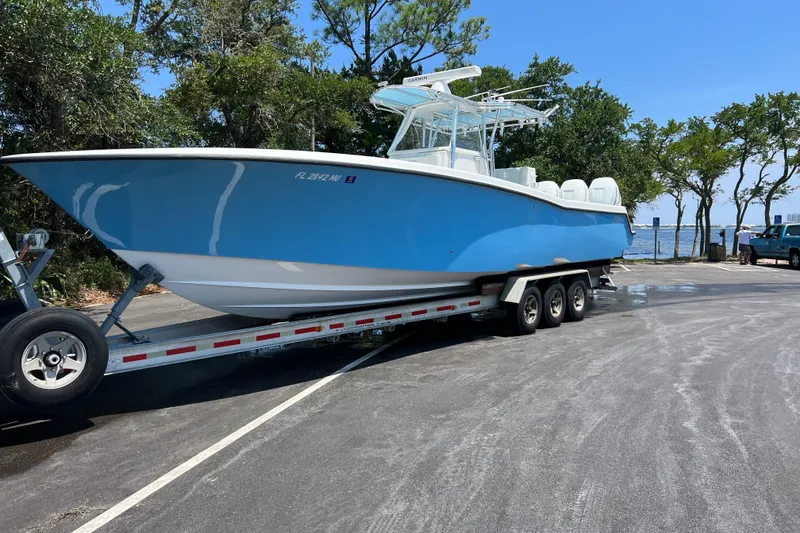 The Image of 2008 Invincible 36 CC boat on trailer, parked near waterfront with trees in background. - 0