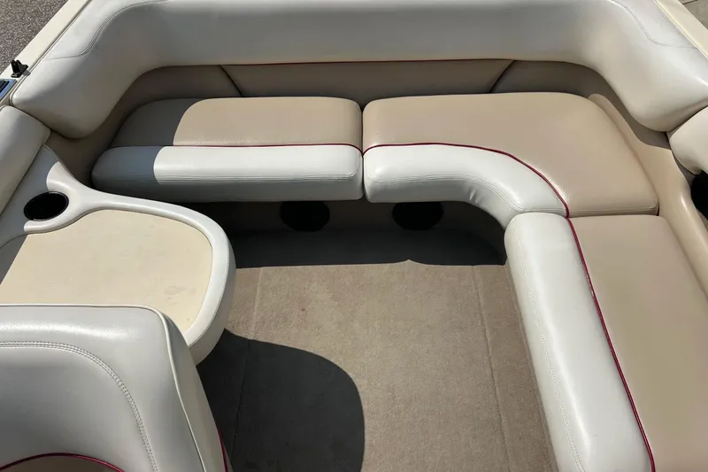 Slide: The Image of 1999 Malibu Sunsetter VLX boat interior with beige and white seating, cup holders, and carpeted floor. - 18