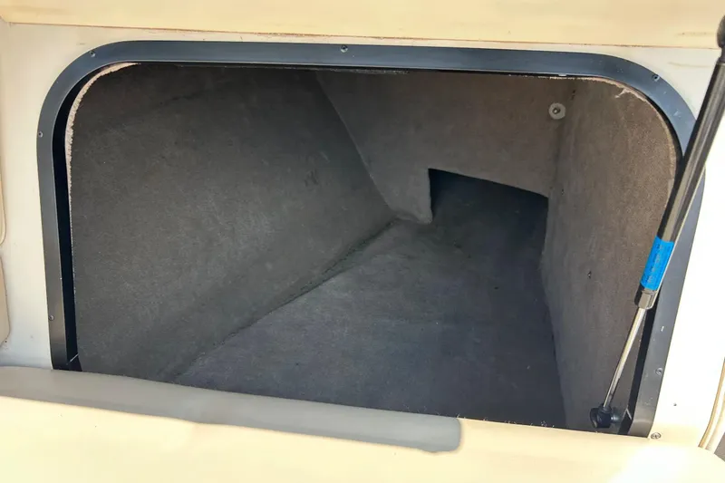 Slide: The Image of Storage compartment of a 1999 Malibu Sunsetter VLX boat, featuring carpeted interior. - 26
