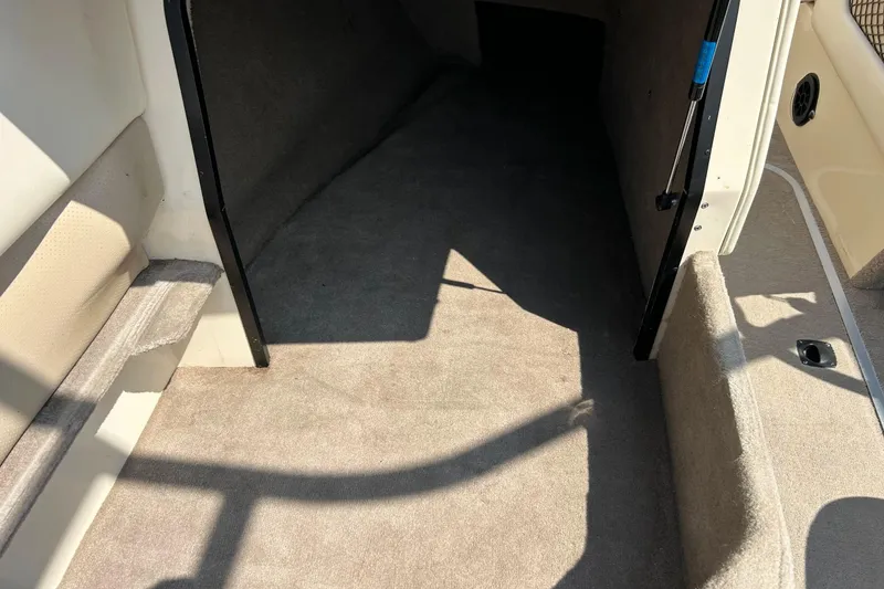 Slide: The Image of Interior of a 1999 Malibu Sunsetter VLX boat, featuring carpeted flooring and seating area. - 27