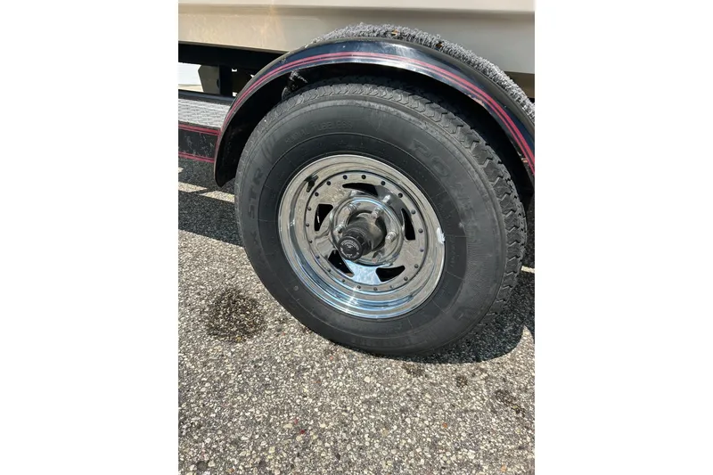 Slide: The Image of Trailer wheel of a 1999 Malibu Sunsetter VLX on asphalt surface. - 3