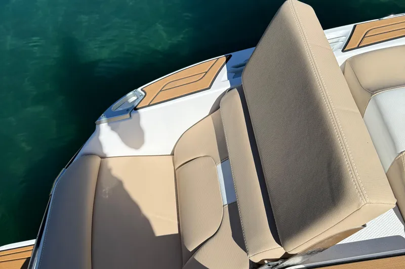 Slide: The Image of 2025 MasterCraft X24 boat with beige seating and teak accents on clear water. - 11