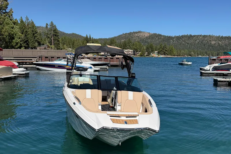 Slide: The Image of 2025 MasterCraft X24 boat docked on a serene lake with scenic mountain backdrop. - 2